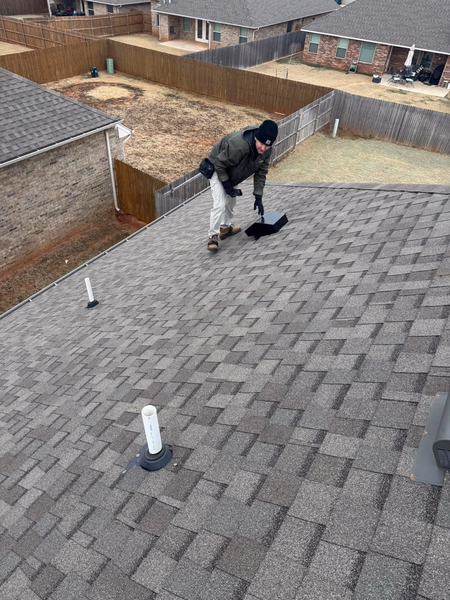Roofer installing new shingles on a residential roof.