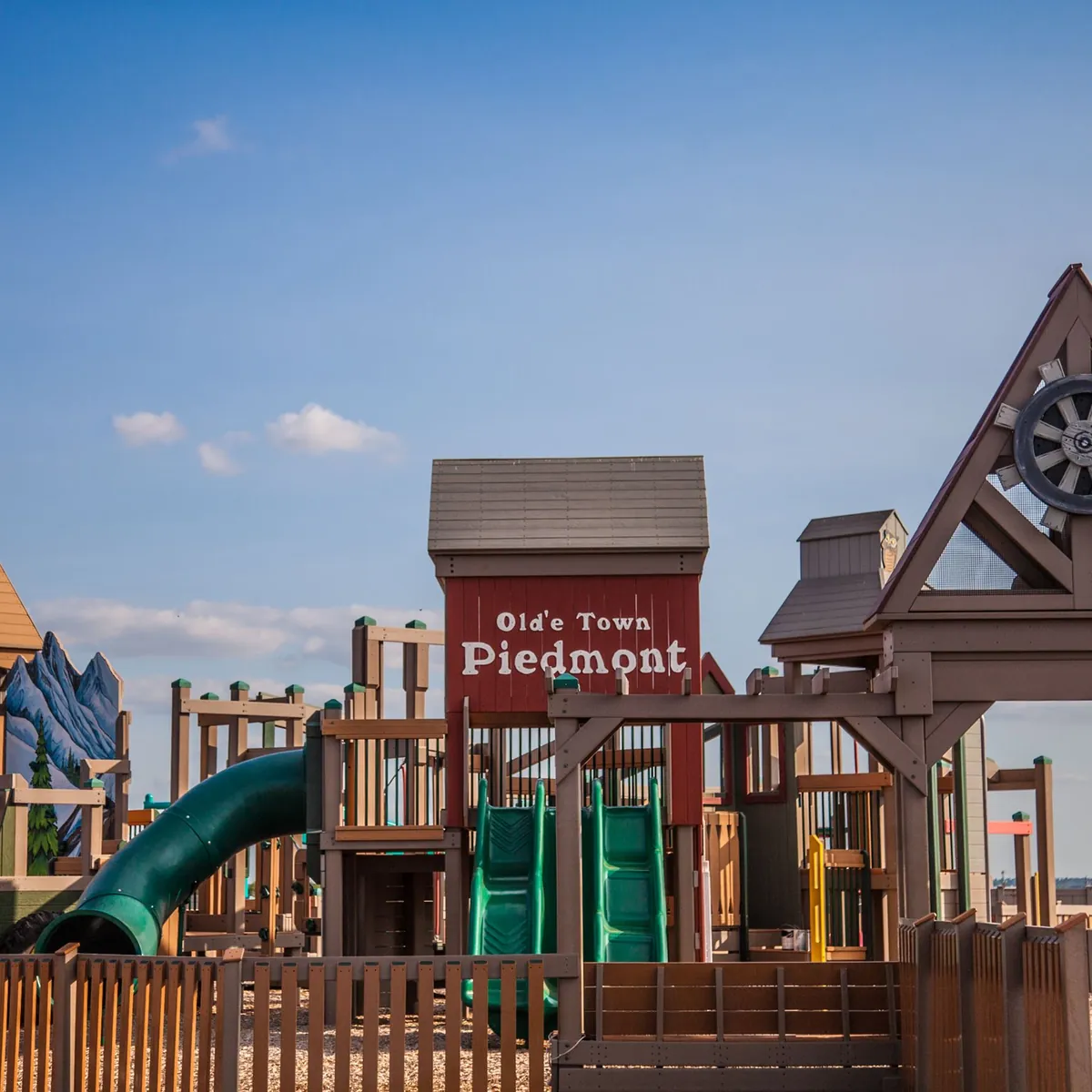 Wooden "Old Town Piedmont" playground with towers and slides under a blue sky in Piedmont, Oklahoma.